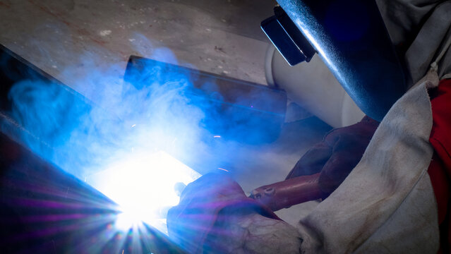 A skilled welder meticulously fuses metal pieces together in a sunlit workshop, sparks erupting from the welding process, creating a vivid display of light and energy