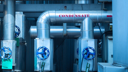 Piping system is seen in a manufacturing setting, highlighting condensate lines and valves. The...