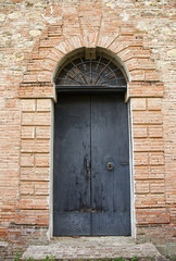 Dark ancient wood doorway in a brick wall at Castle of Serravalle. Bologna, Italy.