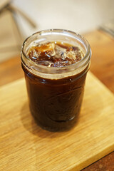 Close up glass of iced black coffee on wooden table
