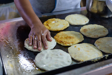 Hand Pressing Pupusas on a Hot Griddle