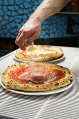Chef sprinkling cheese over traditional pizza