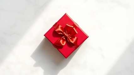 Elegant red gift box tied with a satin ribbon, placed on a sleek marble surface.