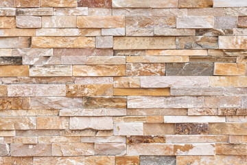 Front or top view of natural stone texture in rectangular shapes arranged in horizontal rows. Beige brown color tones. Construction material for architectural design, engineering and background.