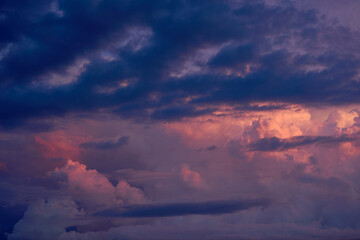 暗い空を背景に夕日に染まる入道雲。夏らしい雲と空の背景用素材。