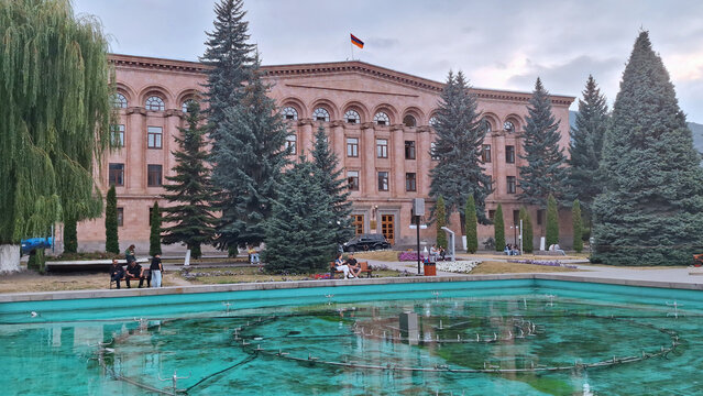 Armenia,Vanadzor-25 August, 2025: Hayk Square in Vanadzor, featuring the regional administration building, a beautiful turquoise fountain, and lush green trees under a cloudy evening sky