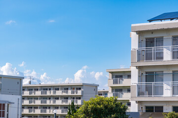 青空の下に建つ集合住宅と白い外壁の団地建物