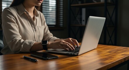Modern Woman Working on Laptop at Wooden Desk with Smartphone and Smartwatch, Focused on Business Task in Office Setting