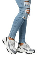 Human legs in light blue ripped skinny jeans & chunky white 'dad' sneakers isolated on a transparent studio background with soft light, confident street style concept