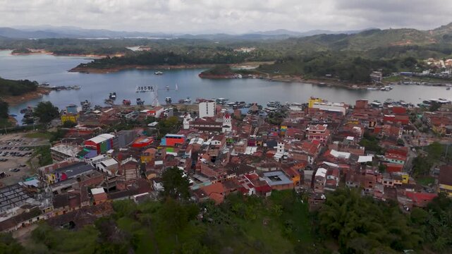 Aerial Drone Descent Towards the Colorful Town of Guatape, Antioquia, Colombia, Showcasing Unique Architecture and Vibrant South American Culture.