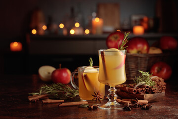 Mulled cider with apples, cinnamon, rosemary, and anise on a background of burning candles.