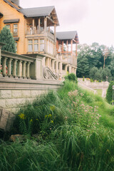 Elegant Wooden Mansion Amidst Lush Greenery and Stone Balustrade