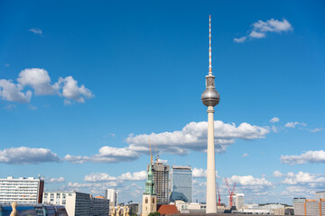 Obraz premium The iconic Berlin TV Tower dominates the skyline. Surrounded by modern high-rises, it rises tall under a clear blue sky.