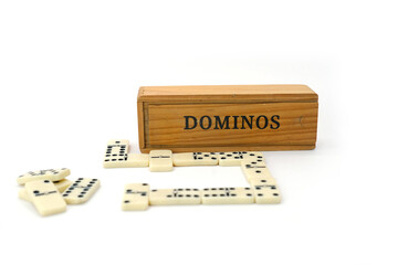 wooden box with the word “Domino” and several white domino tiles placed in front of it, isolated on a clean white background