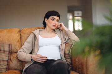 Pregnant Woman sitting on a couch in a relaxed posture while contemplating thoughts during a calm...