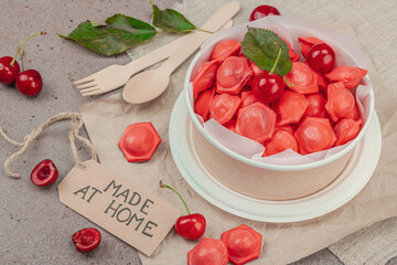 Frozen cherry dumplings in a paper bowl, flat lay composition with fresh cherries, mint, handmade...