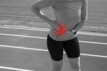 Girl in sportswear in stadium is exhausted and has pain during training and workout.Sports woman has a stomach ache.