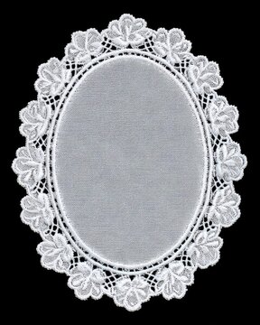 White oval lace doily with delicate elegant floral embroidery on black background