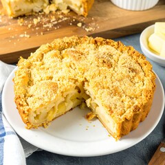 A delectable, golden-brown crumble  pie, sliced and ready to enjoy, sits on a white plate.