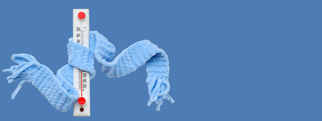 A thermometer wrapped in a cozy blue scarf indicates cold weather
