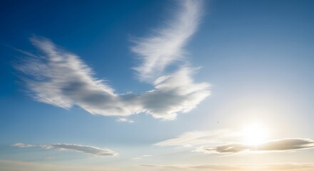 Fototapeta premium Serene blue sky with ethereal white clouds resembling angel wings and a radiant sun shining brightly