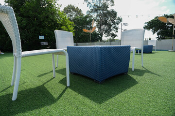 Angle view to woven plastic table and chairs outdoor hangout on the artificial grass.