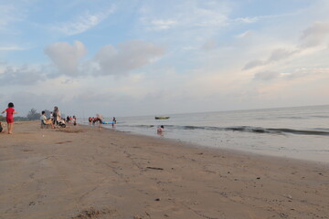 Sunset over calm ocean casting warm glow across the water. Beach sandy under sky is lightly clouded...