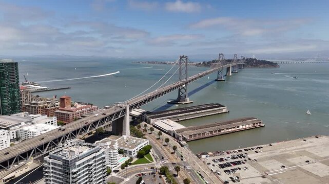 An aerial view captures the Bay Bridge stretching across San Francisco Bay, linking San Francisco and Oakland with its dual decks and striking suspension design.