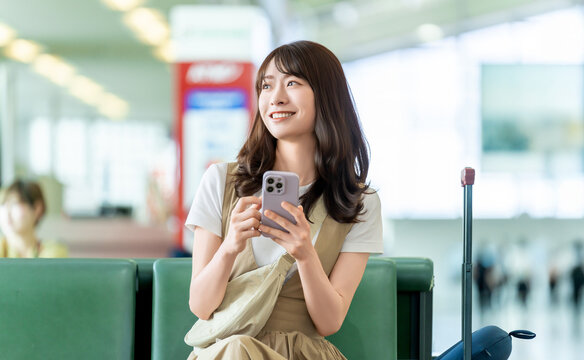 空港でスマートフォンを使う旅行中の女性
