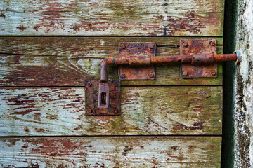 wooden door, old weathered and cracked boards painted red and green color for background or texture