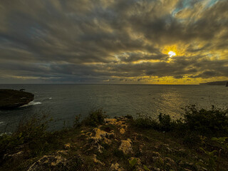 Coastal Sunset Panorama: A mesmerizing coastal landscape unfolds beneath a dramatic sky, with the...