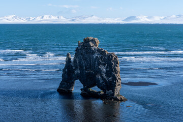 Rock Formation in Ocean with Snowy Mountains