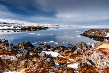 Rocky Coastline with Snow and Calm Water