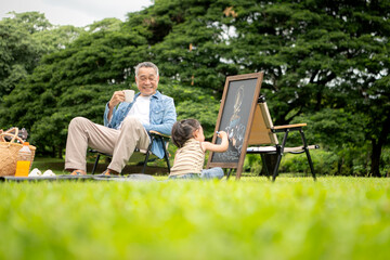 Fototapeta premium Happy multi generational Asian family enjoying picnic in the park