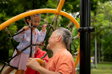 A grandfather plays with his granddaughter at the playground before jogging together in the park