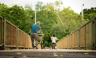 Grandfather and little girl to ride balance bike in park on the holidays of the week