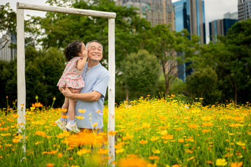 Grandfather and granddaughter stroll through a large flower garden