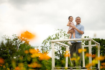 Grandfather and granddaughter stand on scaffolding and admire the beautiful flowers