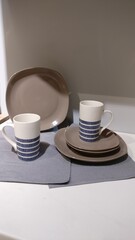Stack of plates and a cups on a neutral surface. Minimalist tableware arrangement with clean lines,...