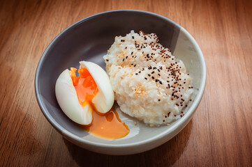 Rice porridge with hard-boiled eggs with uncooked yolks, sprinkled with white and black sesame seeds.