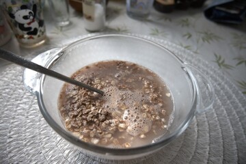 Chocolate flavored oatmeal powder prepared with water in a clear glass bowl, close-up.