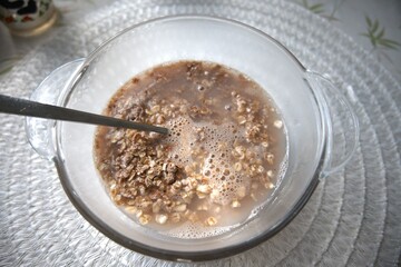 Chocolate flavored oatmeal powder prepared with water in a clear glass bowl, close-up.