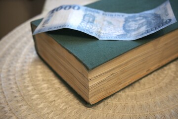 Hungarian 1000 forint banknote placed on a green book symbolizing the value of knowledge.