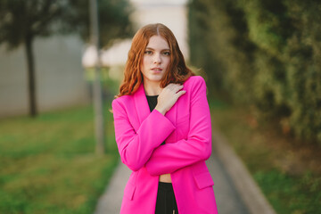 A Chic Young Woman is Posing Outdoors in a Bright Pink Blazer, Radiating Confidence and Style