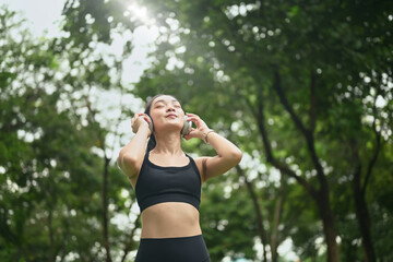 Sporty woman relaxing after exercise, listening to music with eyes closed