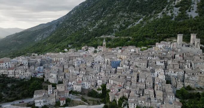 Aerial view of the historic town of Pacentro nestled against a lush mountain with an ancient castle, a tapestry of stone architecture, Pacentro, Abruzzo, Italy.