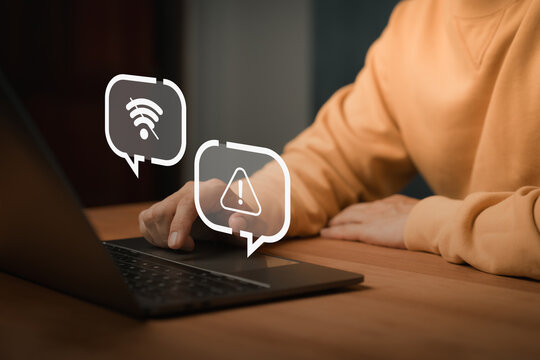 Person using laptop computer with no Wi-Fi and warning alert icons, representing connection failure, network error, internet outage issue, network failure, offline mode and technology disruption.