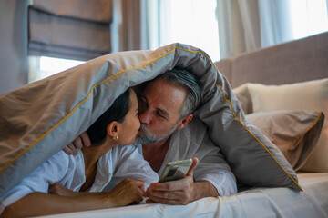 Couple is playing smartphone at bedroom.