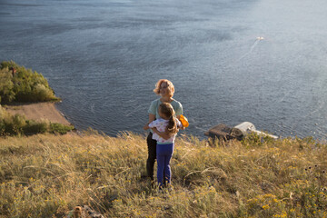 Happy family mom and child daughter stand hugging each other on a mountain by the sea. copy space....