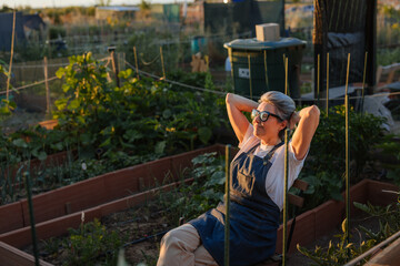 Senior farmer relaxing in her garden at sunset enjoying the fruits of her labor